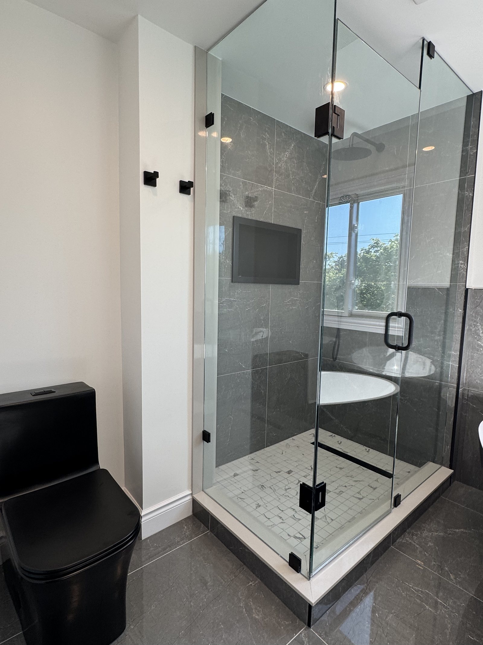 Frameless glass shower with a marble mosaic floor in a renovated ensuite