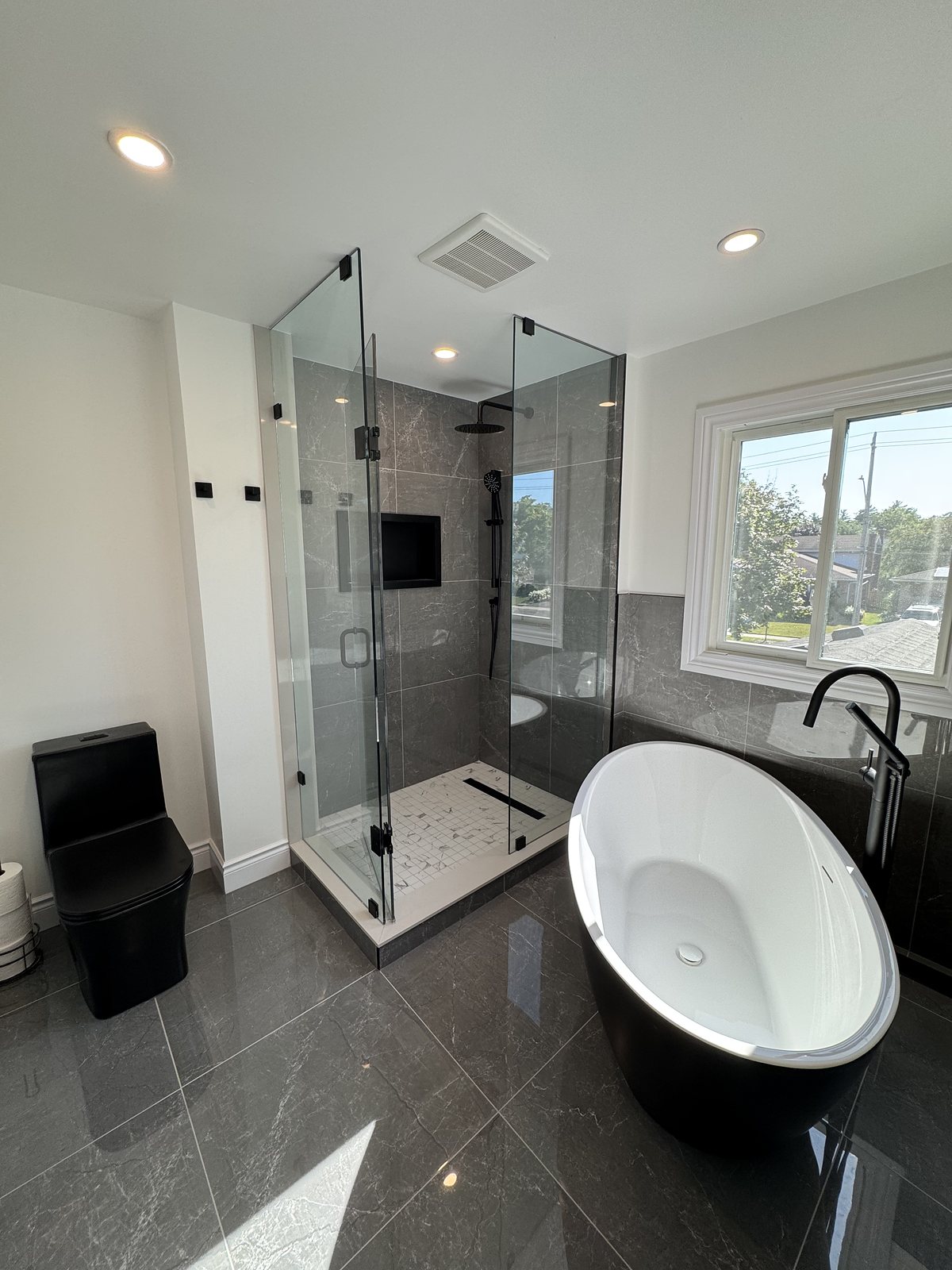 Renovated ensuite with a freestanding tub and dark marble-look tile