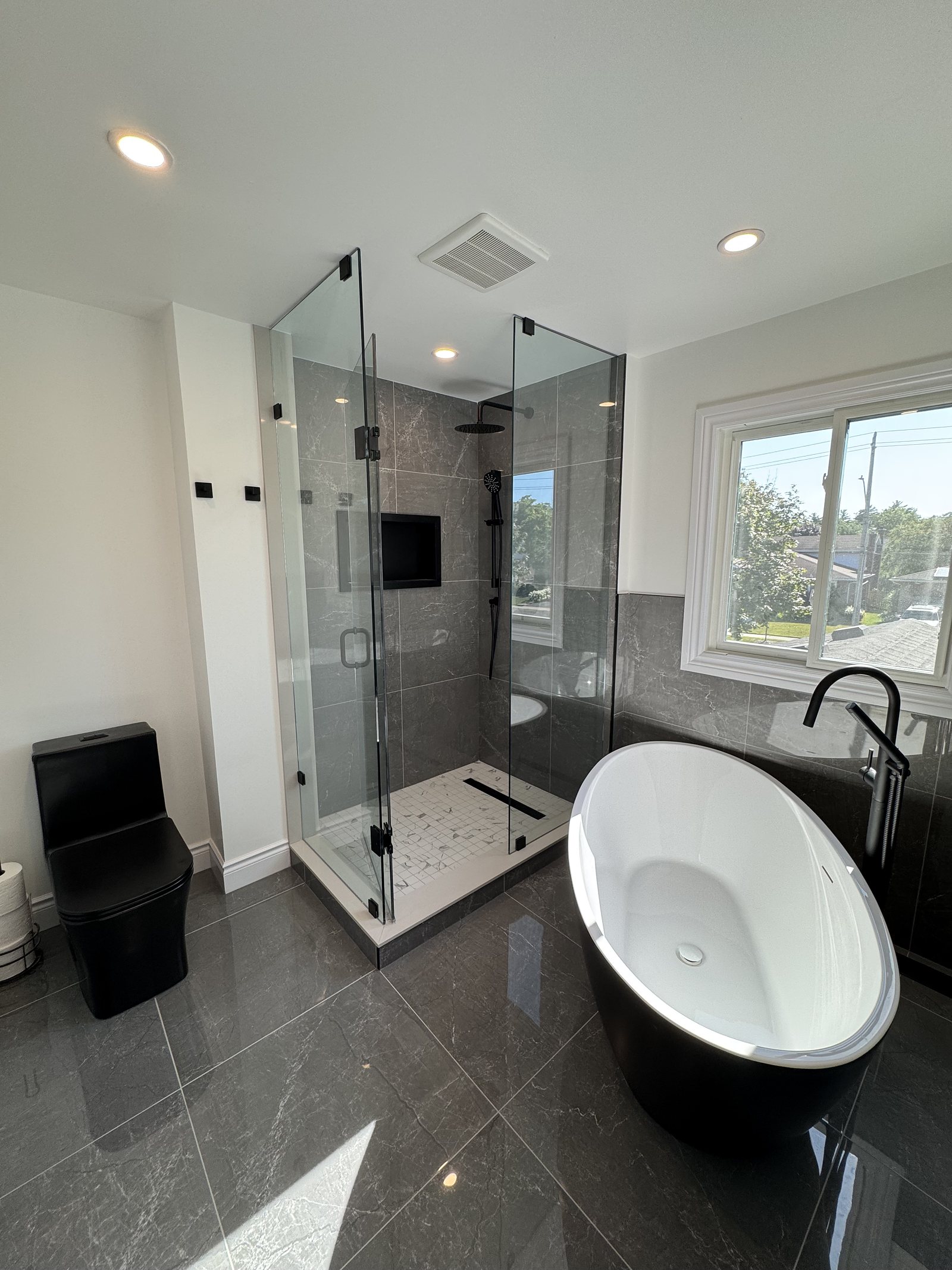 Renovated ensuite with a freestanding tub and dark marble-look tile