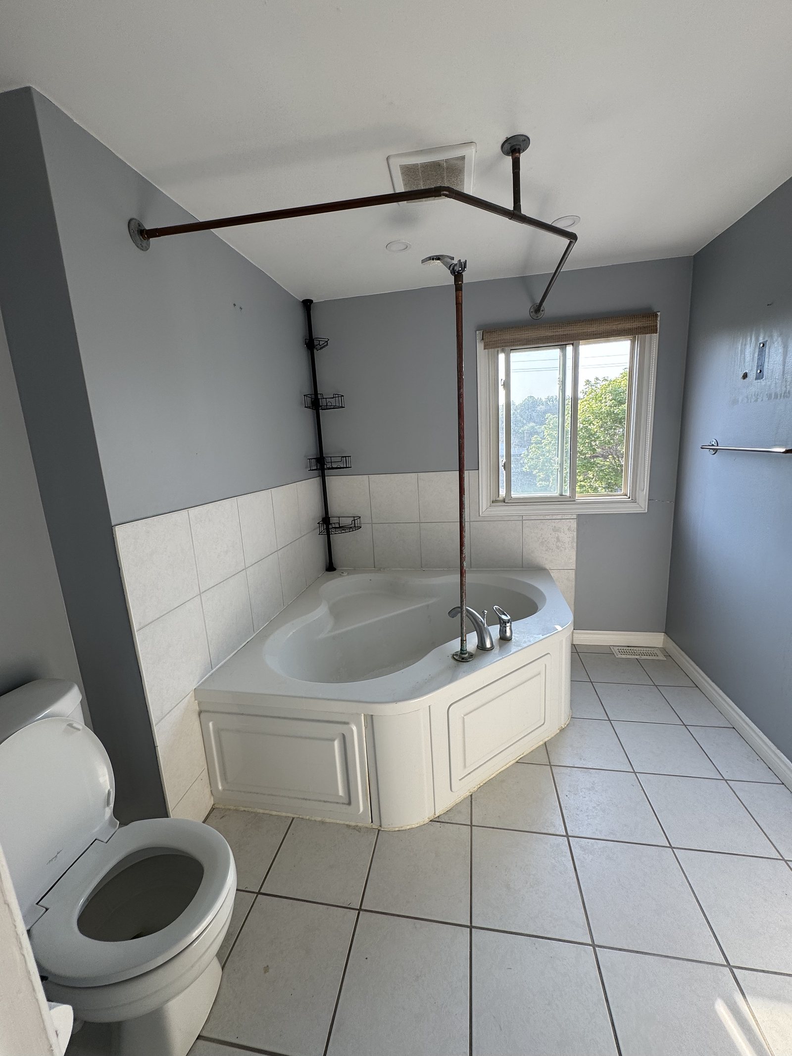 Ensuite before renovation: corner tub, grey walls and white wall tile