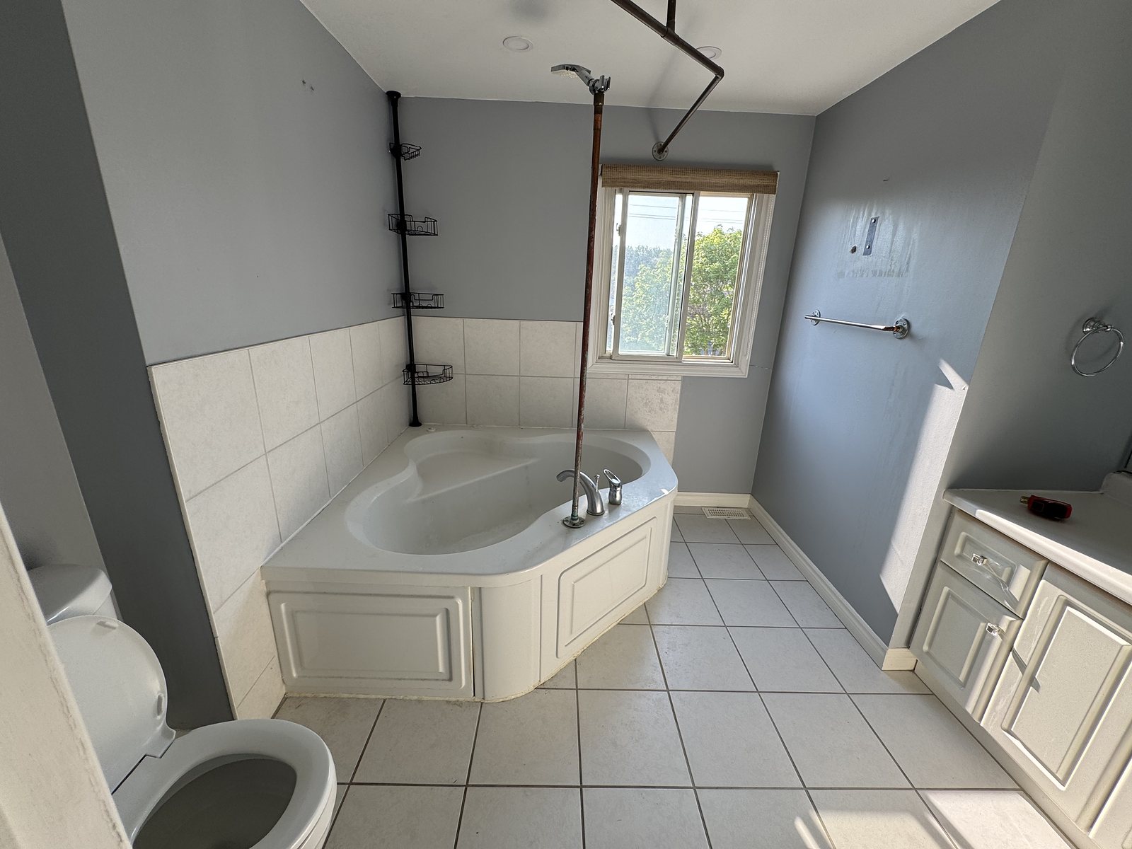 Ensuite before renovation: dated corner tub and builder-grade vanity