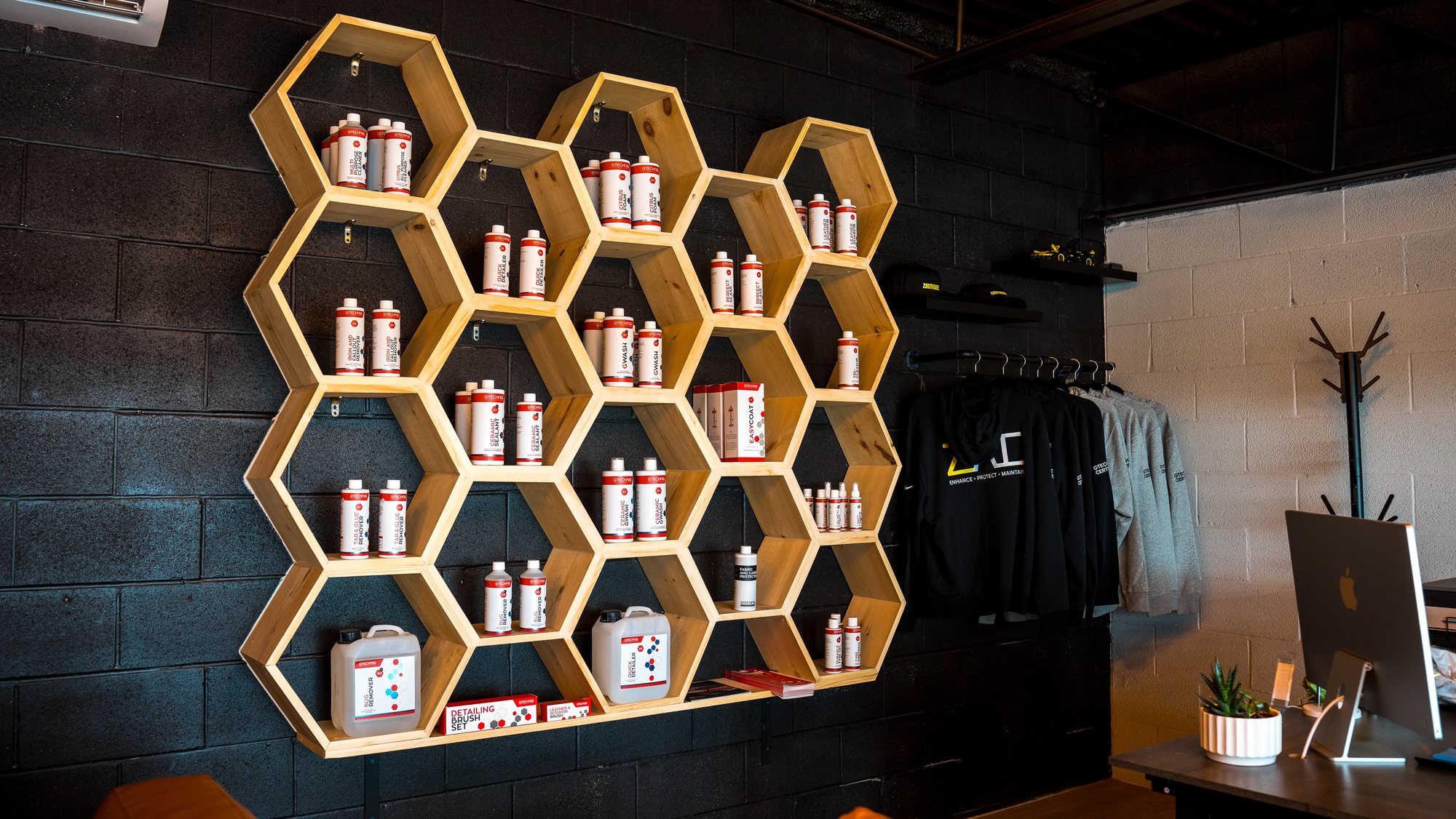 Custom hexagon timber shelving unit mounted on a black block wall with retail display