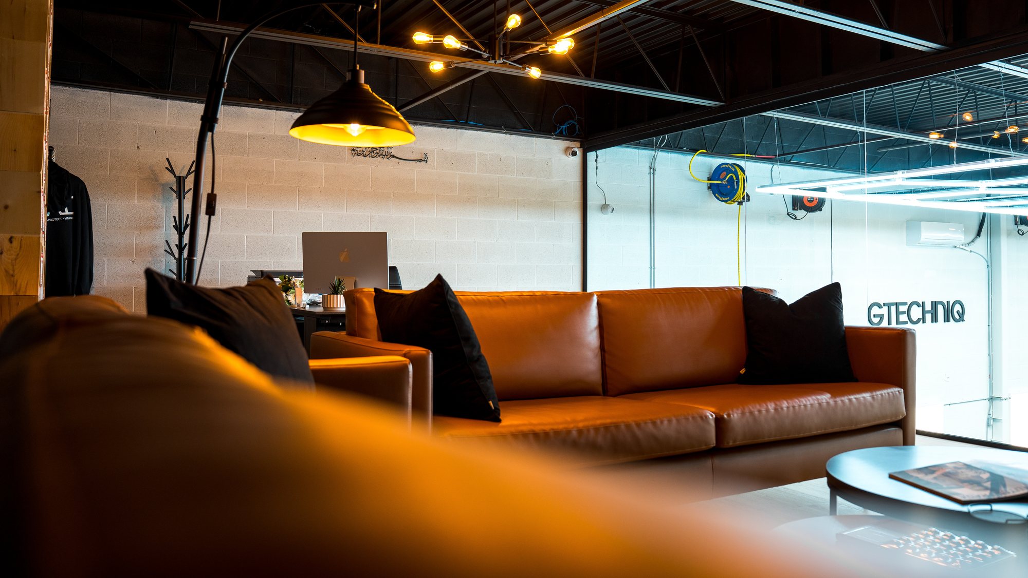 Commercial fit-out with a leather lounge, black block walls and pendant lighting opening onto the shop floor