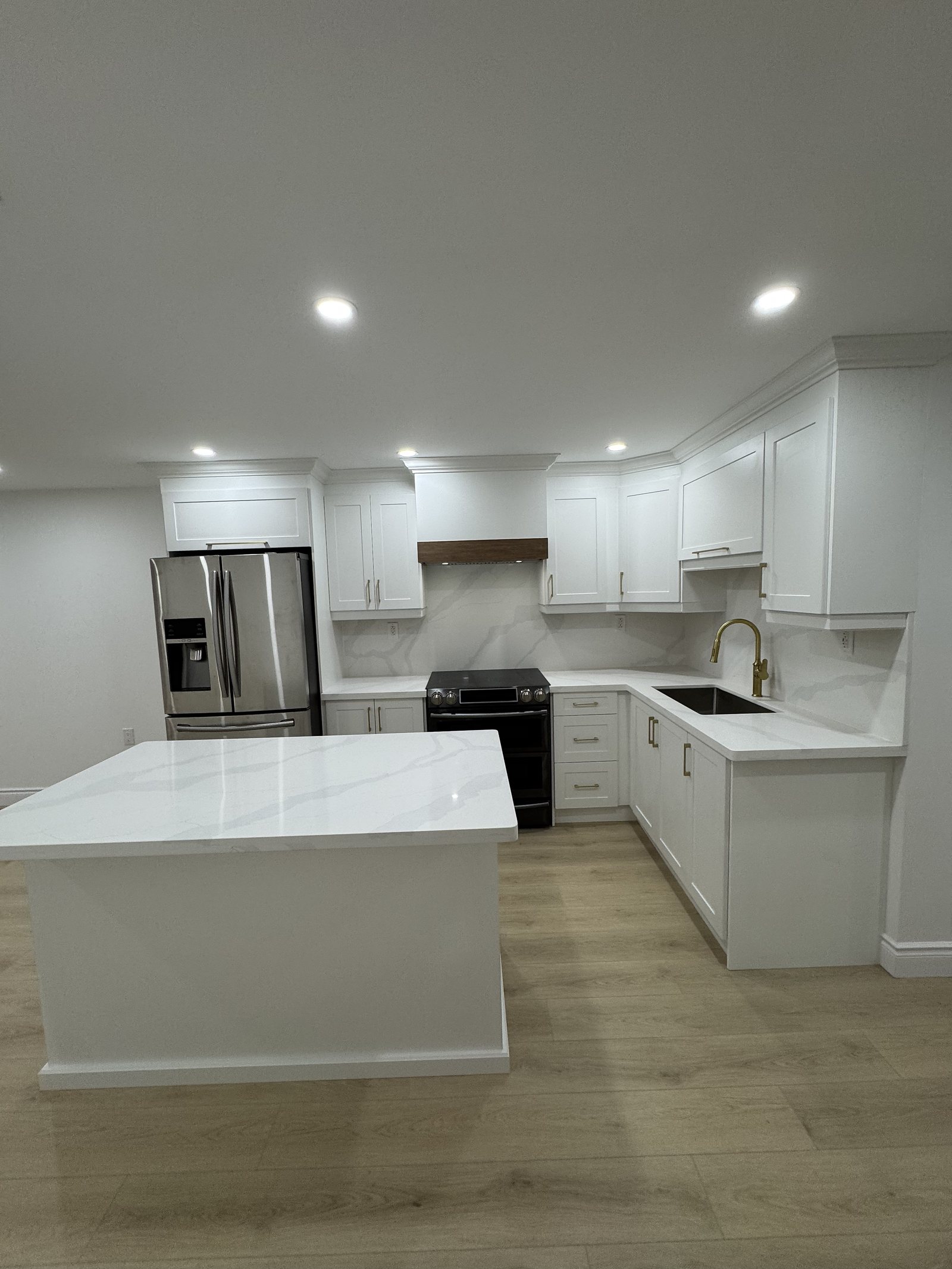 Finished basement kitchen with white cabinetry, quartz island and stainless appliances