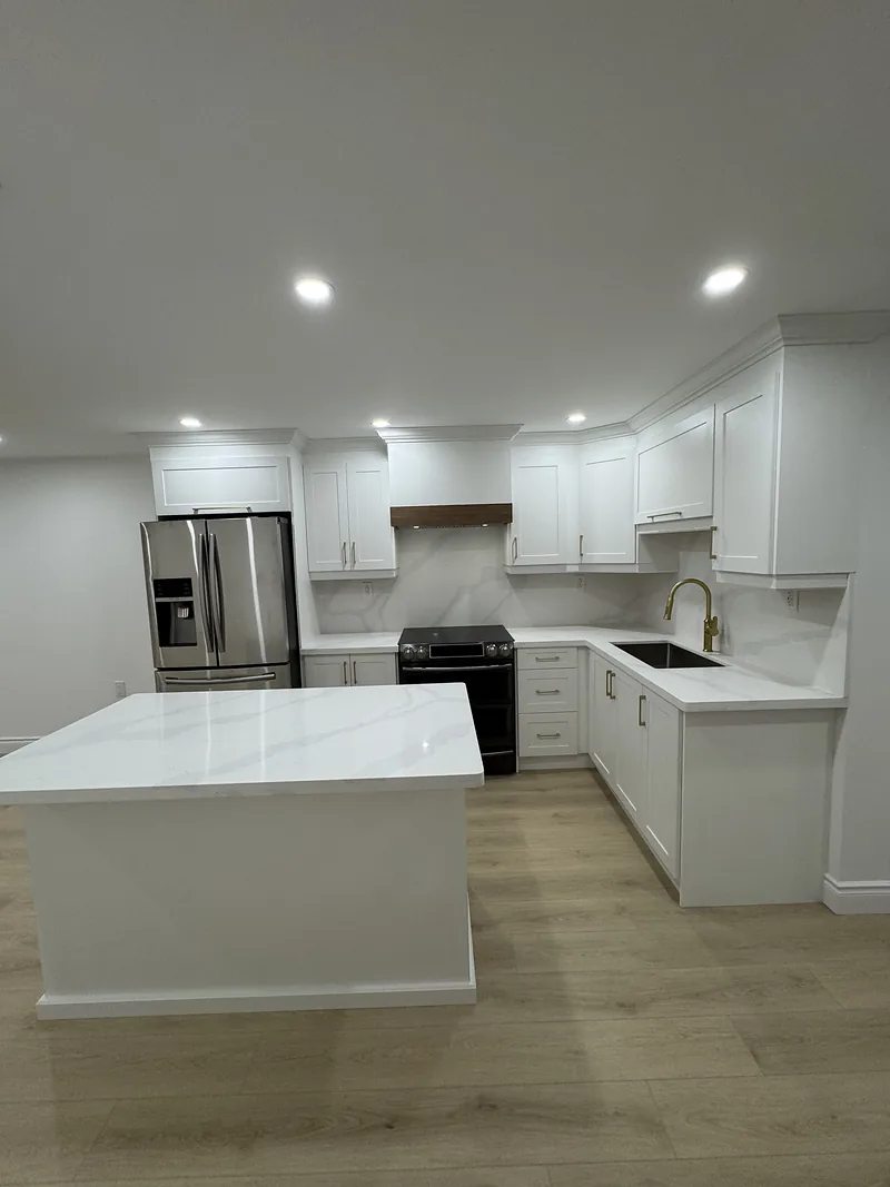 Finished basement kitchen with white cabinetry and a quartz island