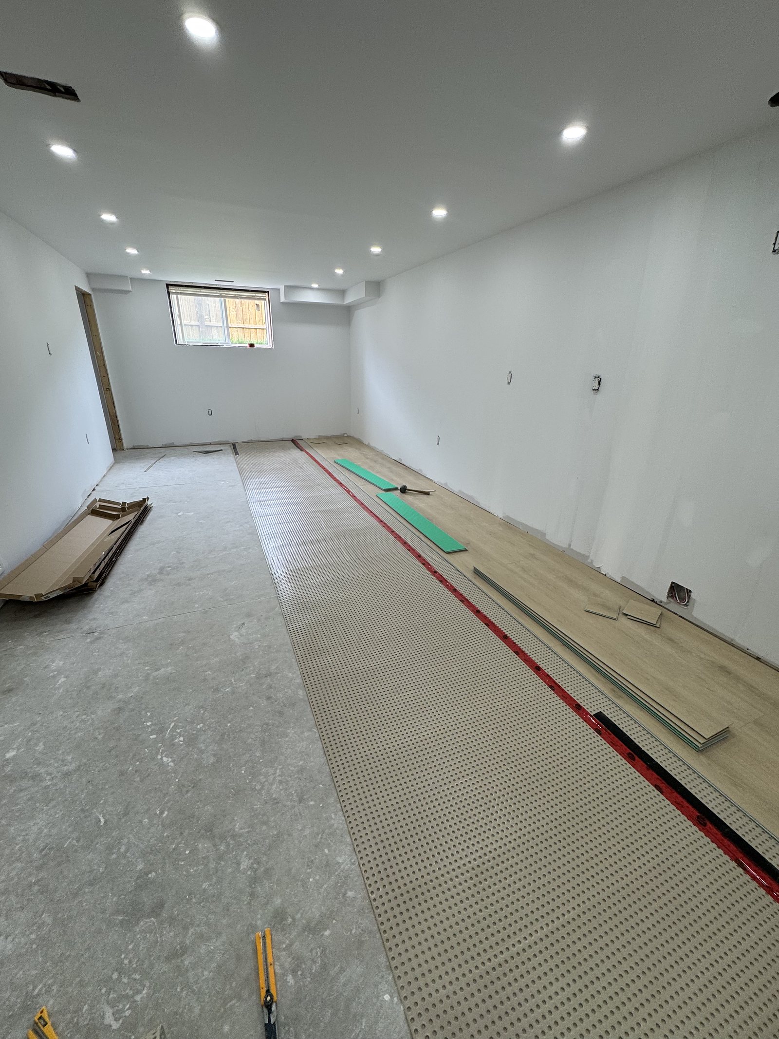 Underlay being installed over a basement floor during a renovation