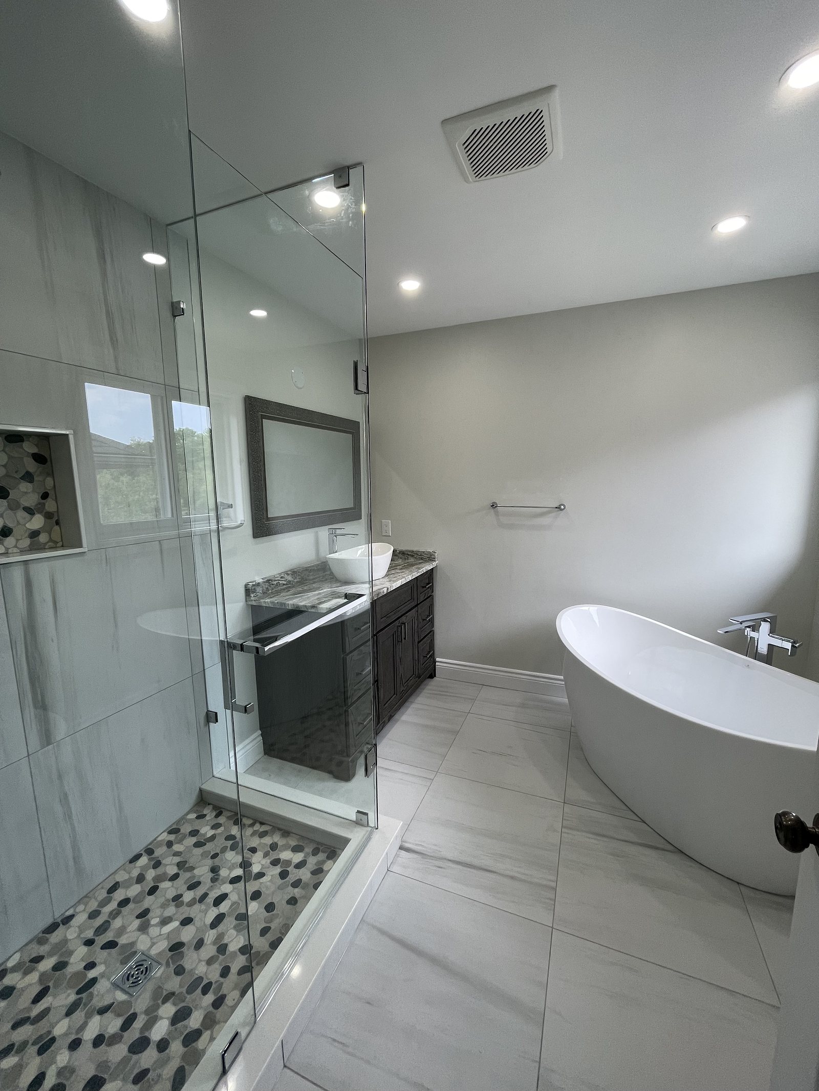 Freestanding soaker tub beside a tiled shower niche in a renovated ensuite