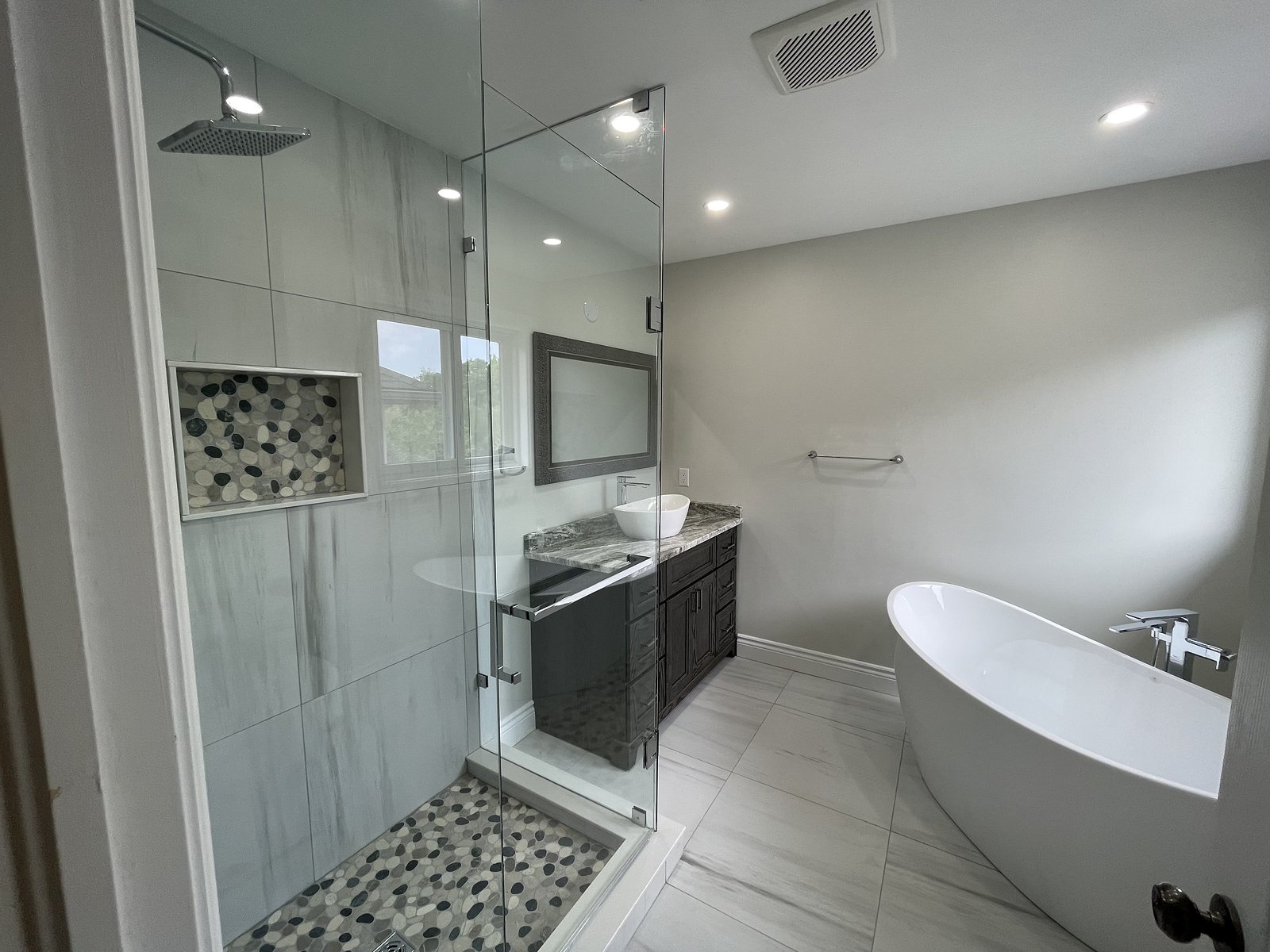 Renovated ensuite with a freestanding tub, glass shower and dark vanity