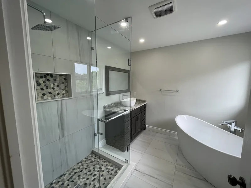 Completed bathroom with a freestanding bathtub, glass shower and dark vanity