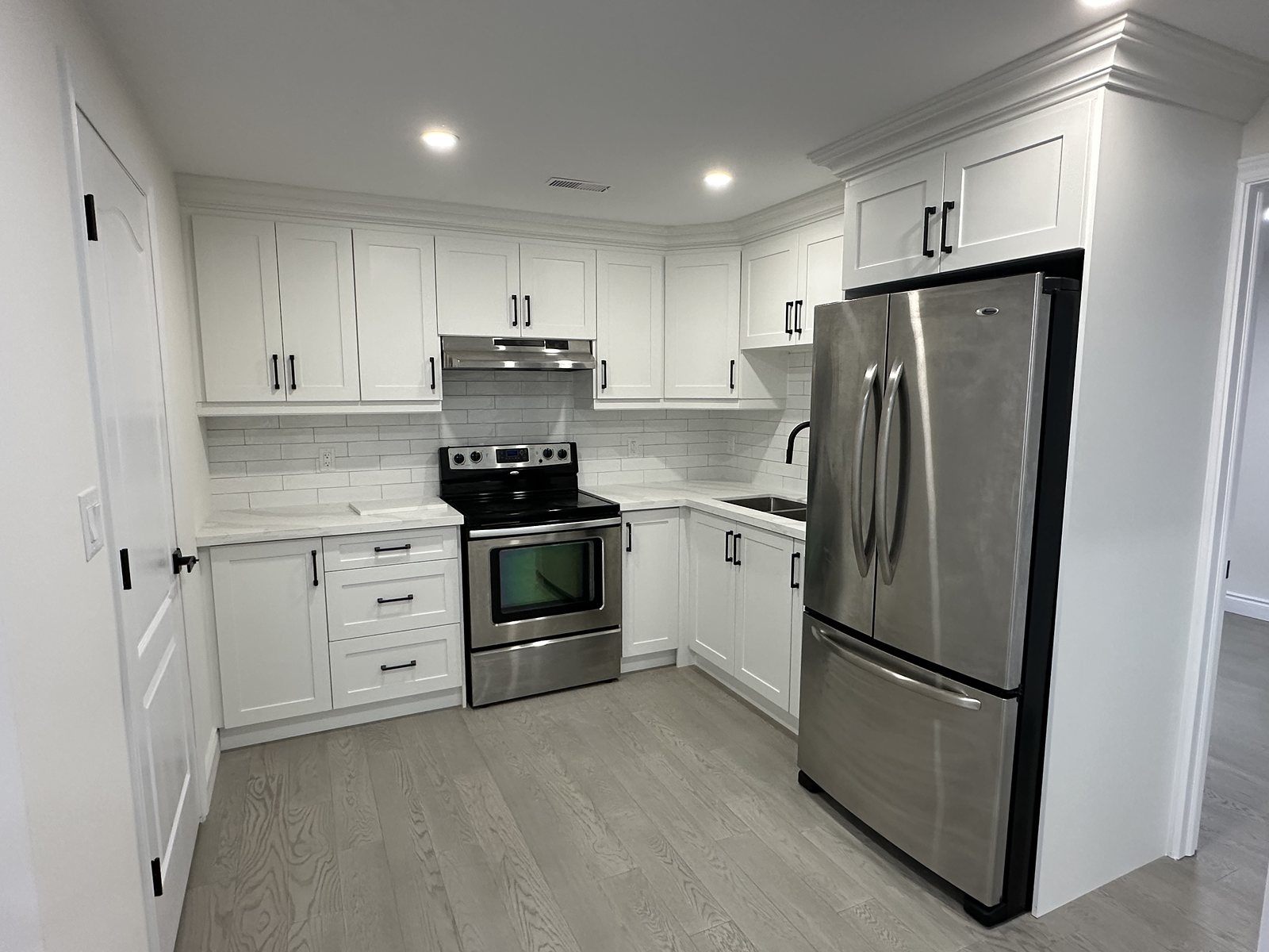 Renovated galley kitchen with white cabinetry and stainless appliances