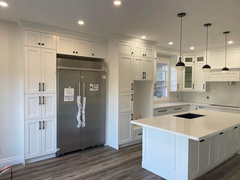 Kitchen with a large quartz island, pendant lighting and floor-to-ceiling cabinetry