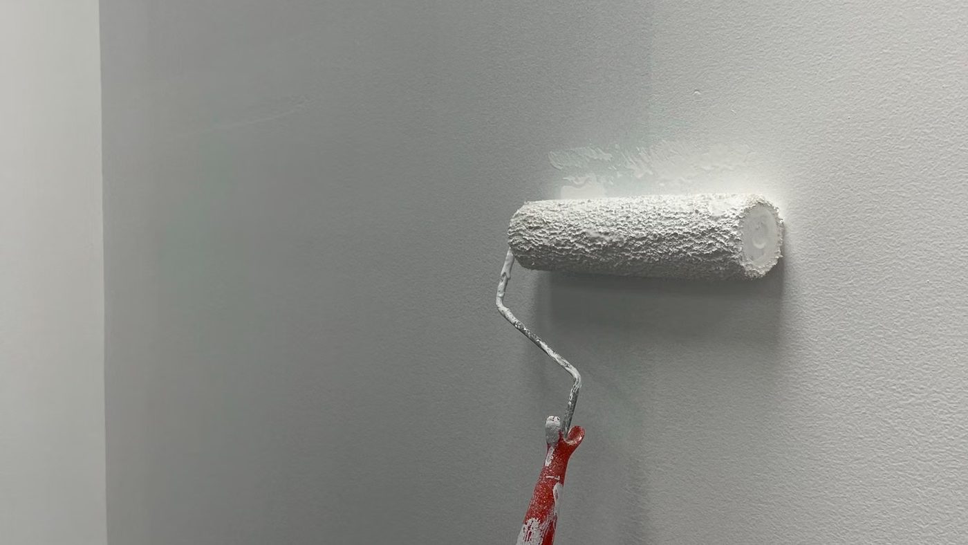 Paint roller applying a smooth even coat to an interior wall