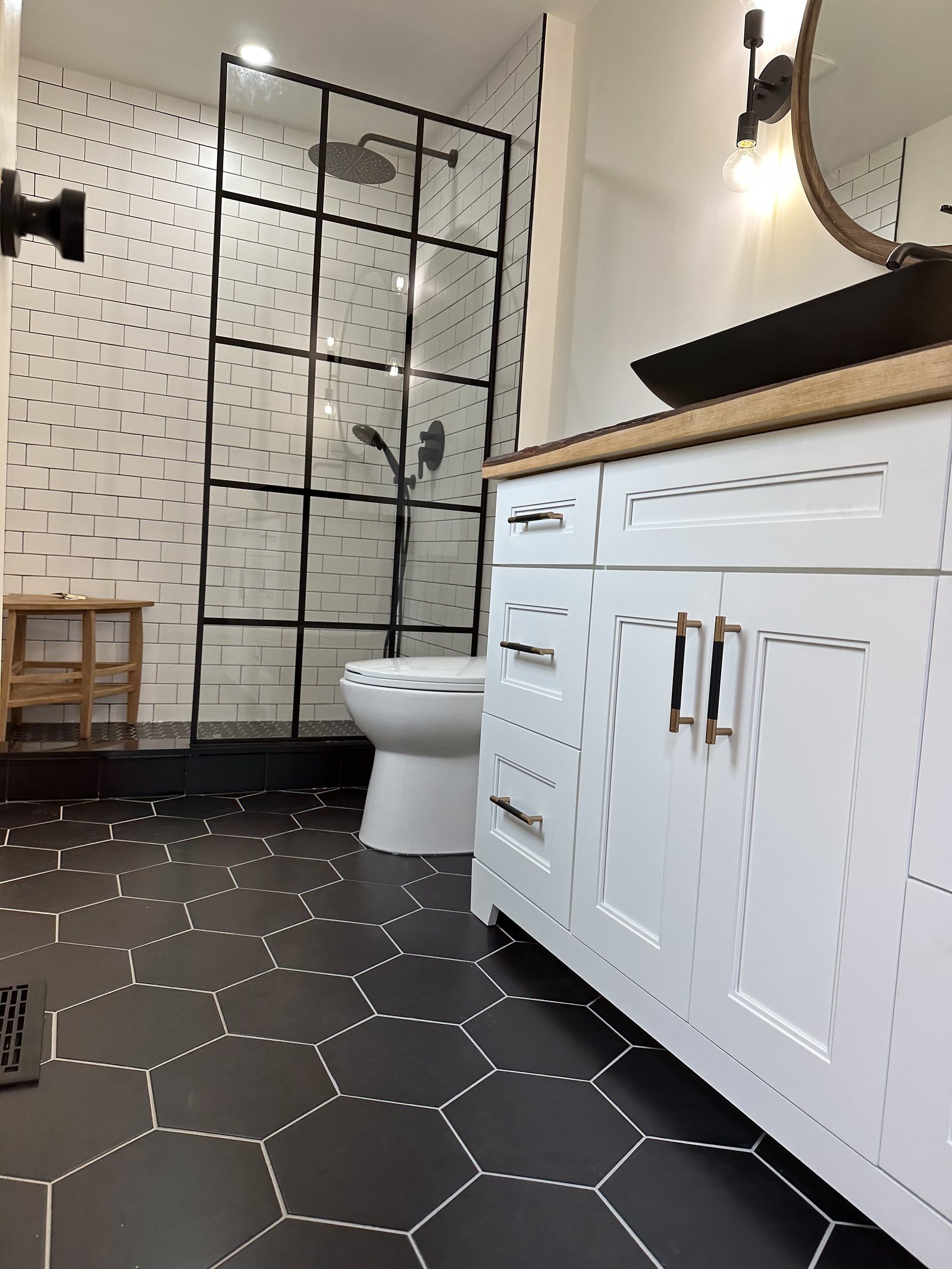 Renovated bathroom with black hexagon floor tile and white subway walls