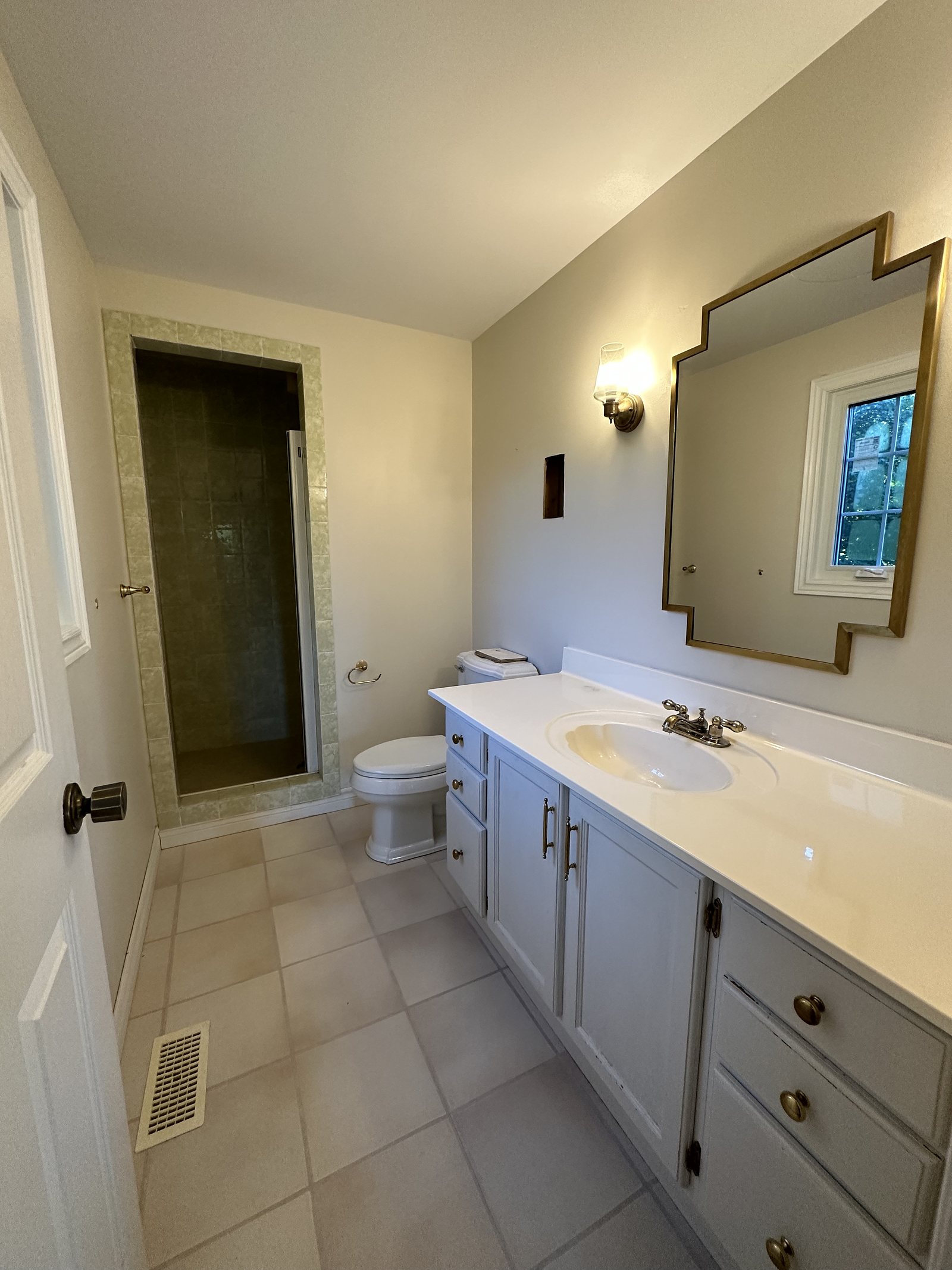 Bathroom before renovation: builder-grade vanity and beige tile